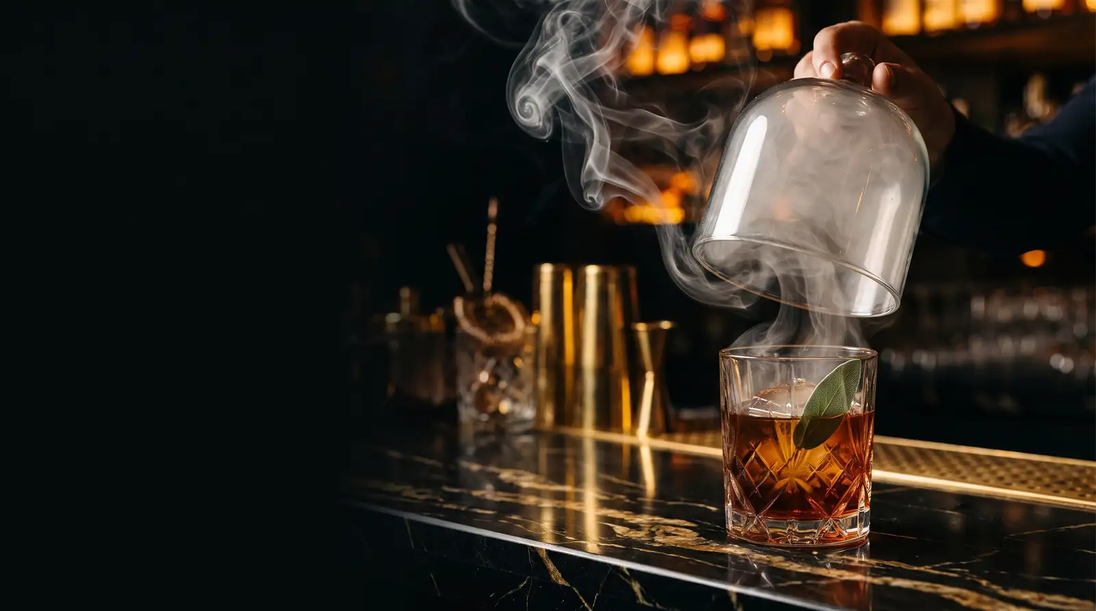 Cóctel de whiskey japonés ahumado bajo campana de cristal sobre barra de mármol